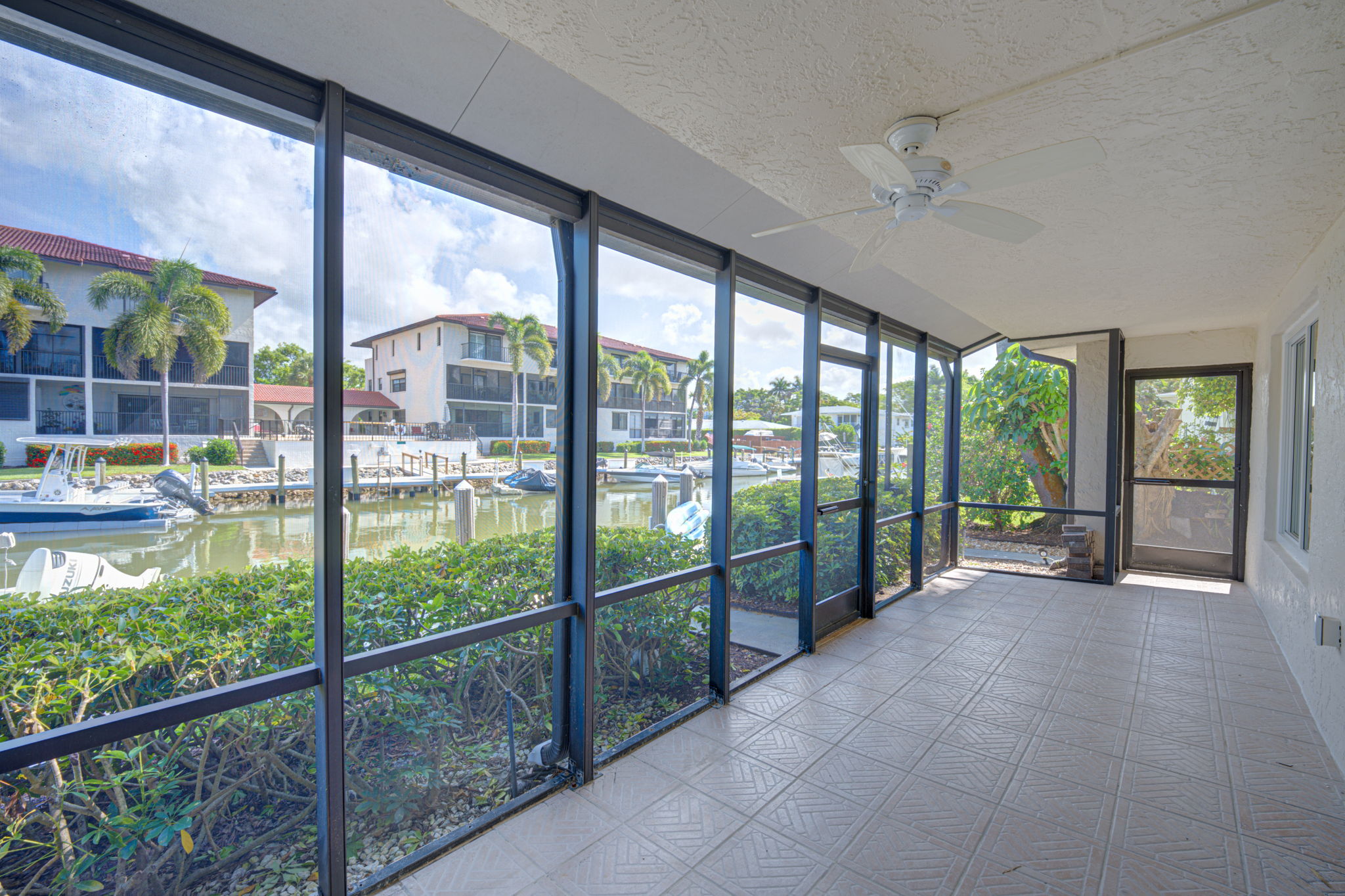 Alternate lanai perspective showing the aluminum structural framing, screening, and immediate proximity to the community seawall.