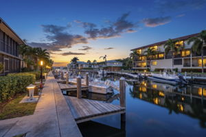 Twilight exterior view highlighting the private boat docks, navigable waterfront canal access, and well-lit community architecture.