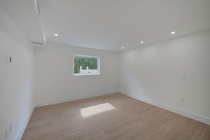 Guest bedroom providing ample natural light through dual impact-resistant windows, finished with baseboard molding and LVP flooring.