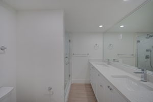 Modernized en-suite bathroom showcasing a frameless glass walk-in shower enclosure with custom floor-to-ceiling tile work.