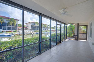 Alternate lanai perspective showing the aluminum structural framing, screening, and immediate proximity to the community seawall.
