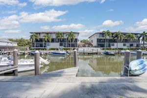 Exterior view from the waterfront walkway showcasing the assigned wooden boat docks, pilings, and immediate Gulf-access canal.