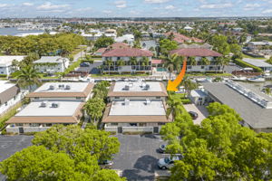Aerial drone shot with an indicator arrow pinpointing the specific unit's location within the community relative to the parking lot.