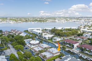Wide aerial landscape with an indicator arrow showing the property's prime coastal location on the residential peninsula.
