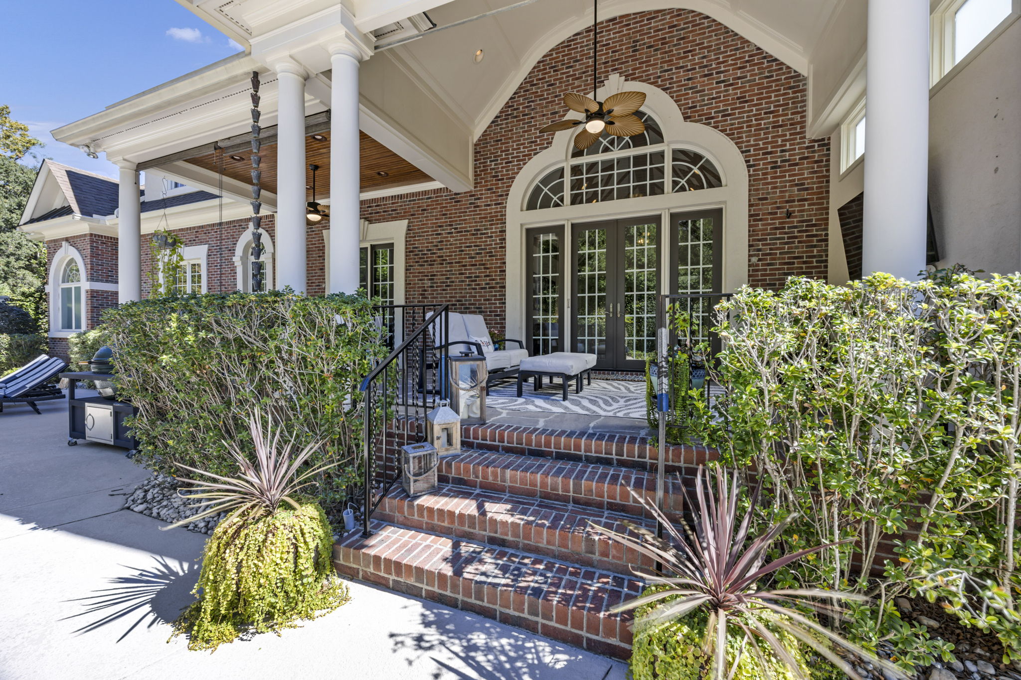 back porch w vaulted ceiling; tongue & groove ceiling; TV; iron railing; 2 sets of french doors