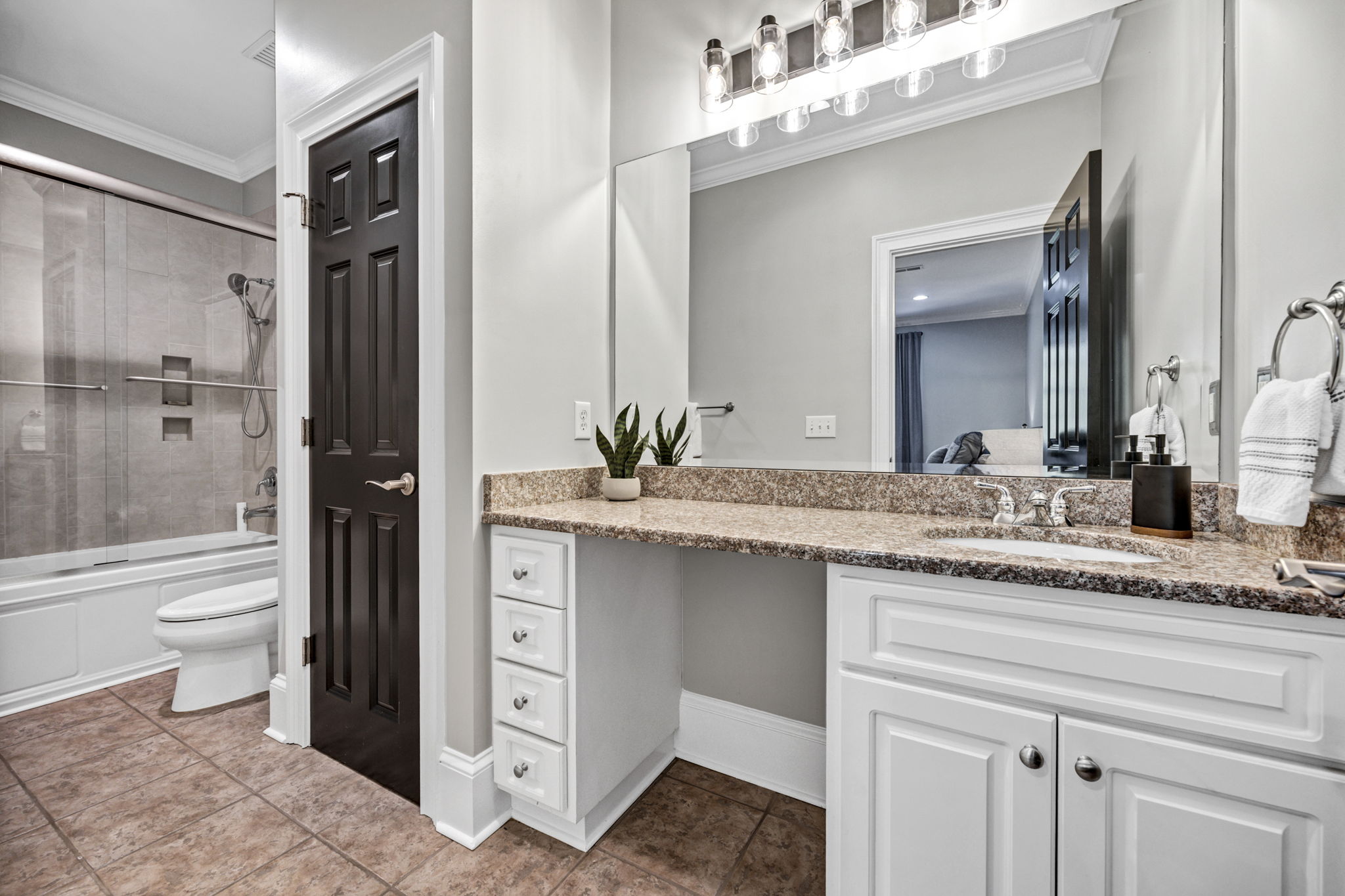 upstairs bedroom 2 ensuite bath with linen closet and elongated granite vanity counter, tiled shower with glass doors