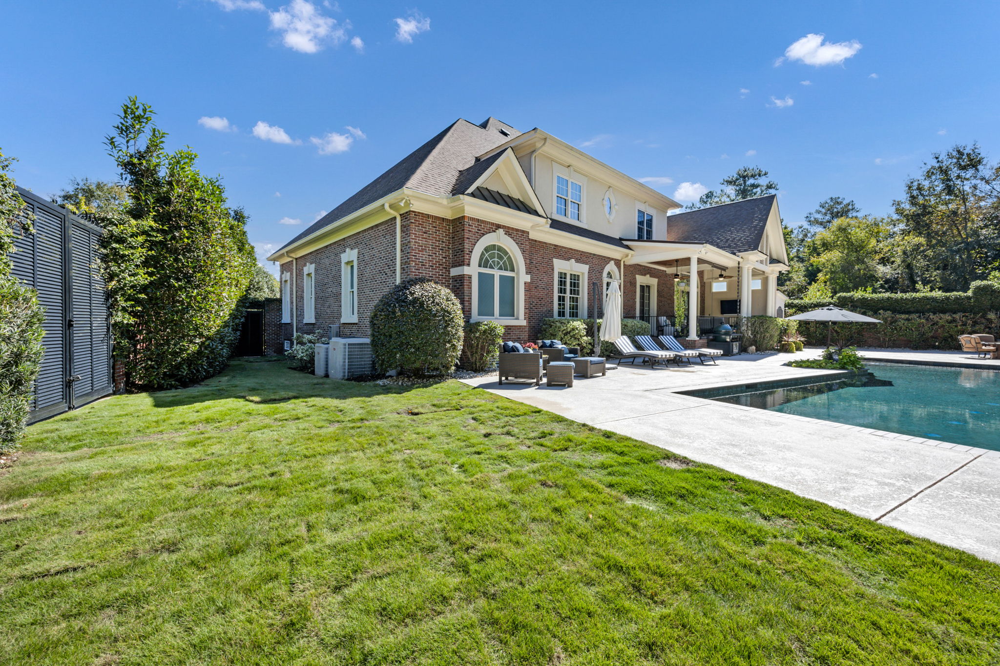 newly created grassy area in back yard.  Double iron gates to the side; single gate to the front.  Also 2 Rinnai tankless water heaters and 2 of 4 Bryant ACs on this side.