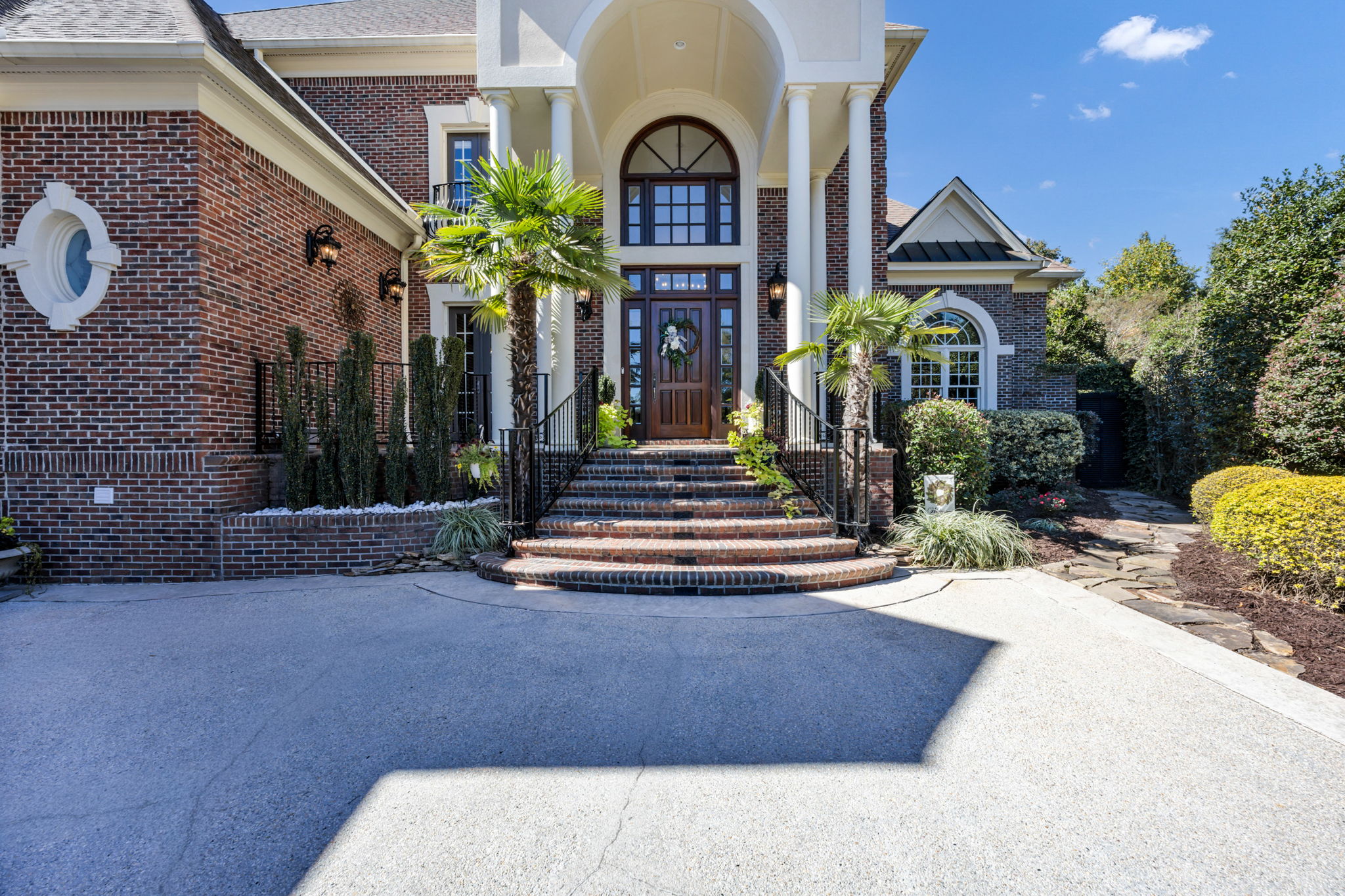 stone pathway to the right leads to iron gate opening to backyard oasis