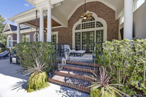 back porch w vaulted ceiling; tongue & groove ceiling; TV; iron railing; 2 sets of french doors