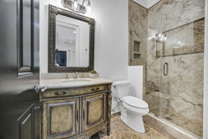 guest ensuite bath has tiled shower with frameless glass