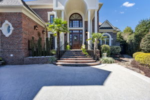 stone pathway to the right leads to iron gate opening to backyard oasis