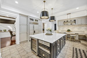 Sub-Zero Refrigerator and Freezer with custom paneling is flanked by deep pantry cabinets.  Sub-Zero, dual-zone wine refrigerator; Wolf drawer microwave