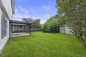 Fenced backyard featuring a patio and a storage unit