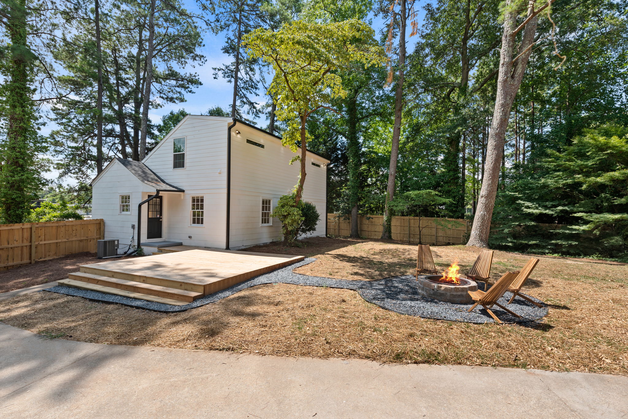 Backyard - Open the kitchen door to reveal a stunning backyard retreat, complete with an expansive deck that seamlessly connects indoor and outdoor living. Enclosed by privacy fences, this serene space offers a large deck for gatherings, a cozy fire pit, and beautiful landscaping that enhances the peaceful ambiance.