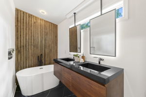 Primary Suite Bathroom - Experience ultimate relaxation in this spa-inspired bathroom, complete with a freestanding soaking tub, walk-in shower, and dual walnut floating vanity.