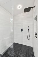 Primary Suite Bathroom Walk-In Shower - Step into the large walk-in shower featuring a rainfall shower head, separate handheld, and a built-in niche for your bath essentials.