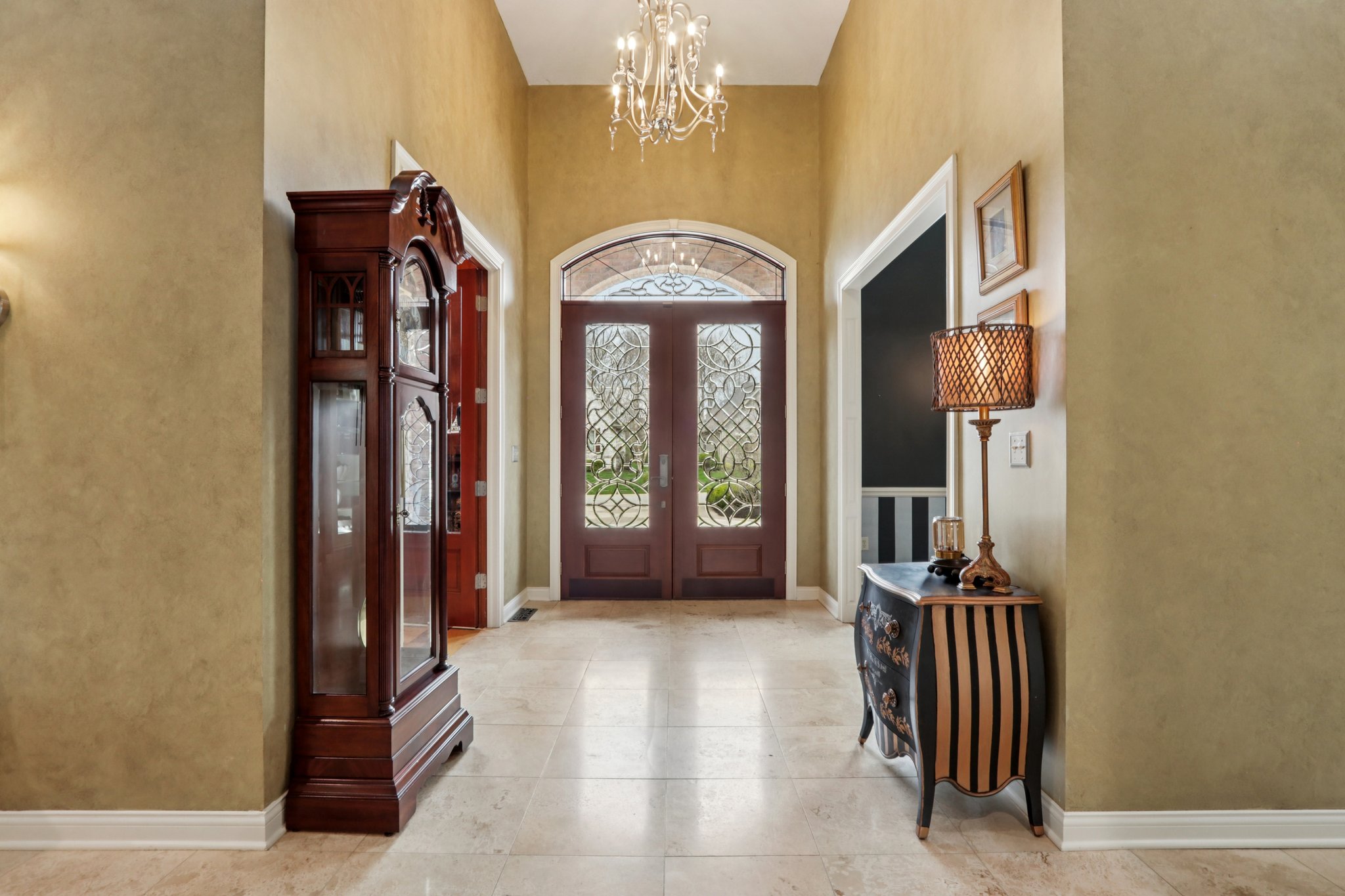 Grand foyer offers soaring ceiling and French doors with elegant lighting
