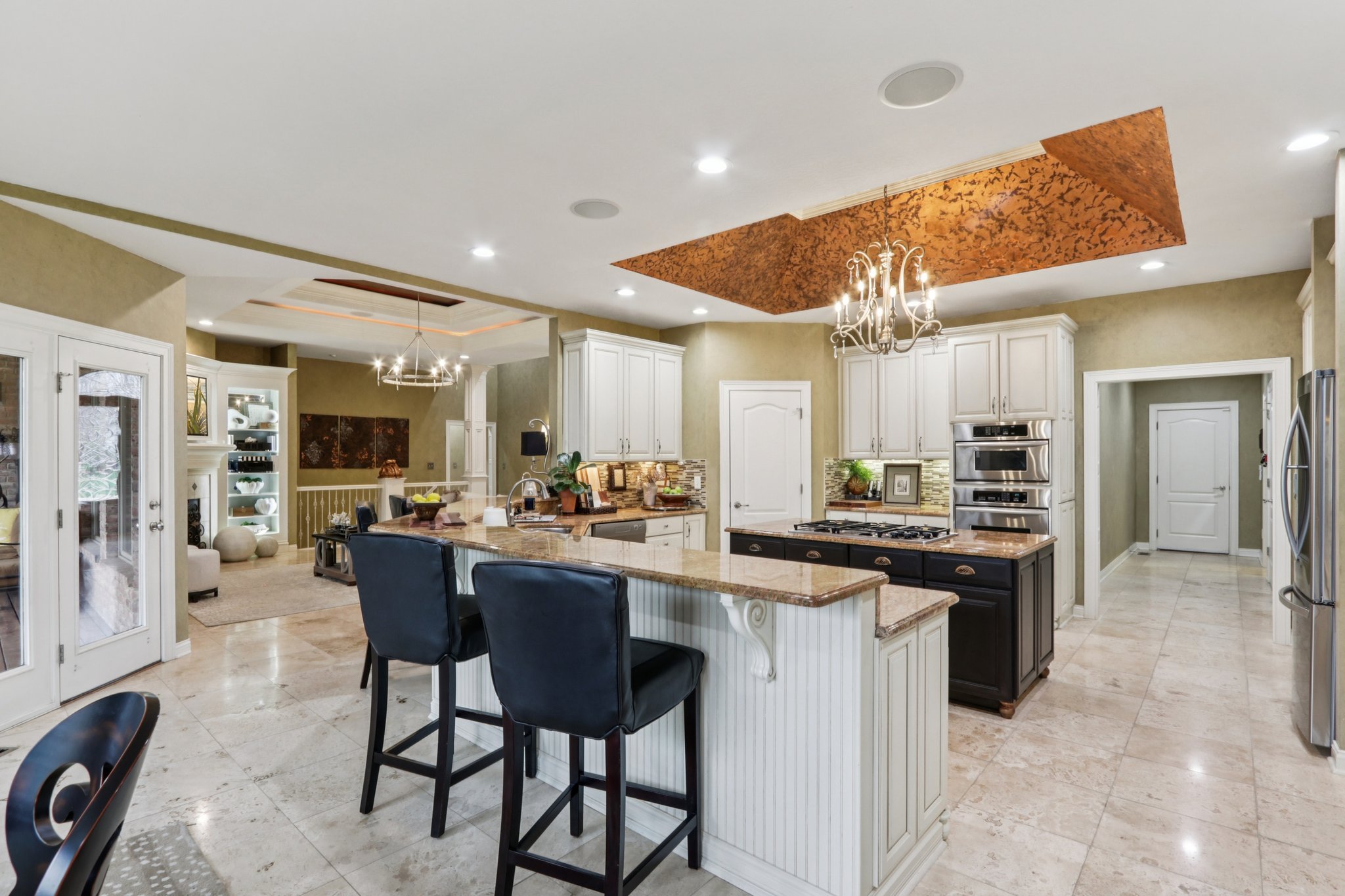 Gourmet kitchen is the heart of the home offering bar seating, tray ceiling, center island with gas cooktop, coffee bar area, plenty of cabinet and counter space, and stainless steel appliances