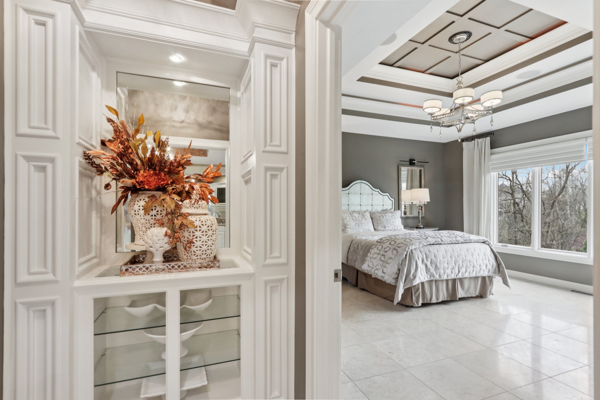 Primary bedroom suite offers ornamental molding, tray ceiling, and great views to the backyard