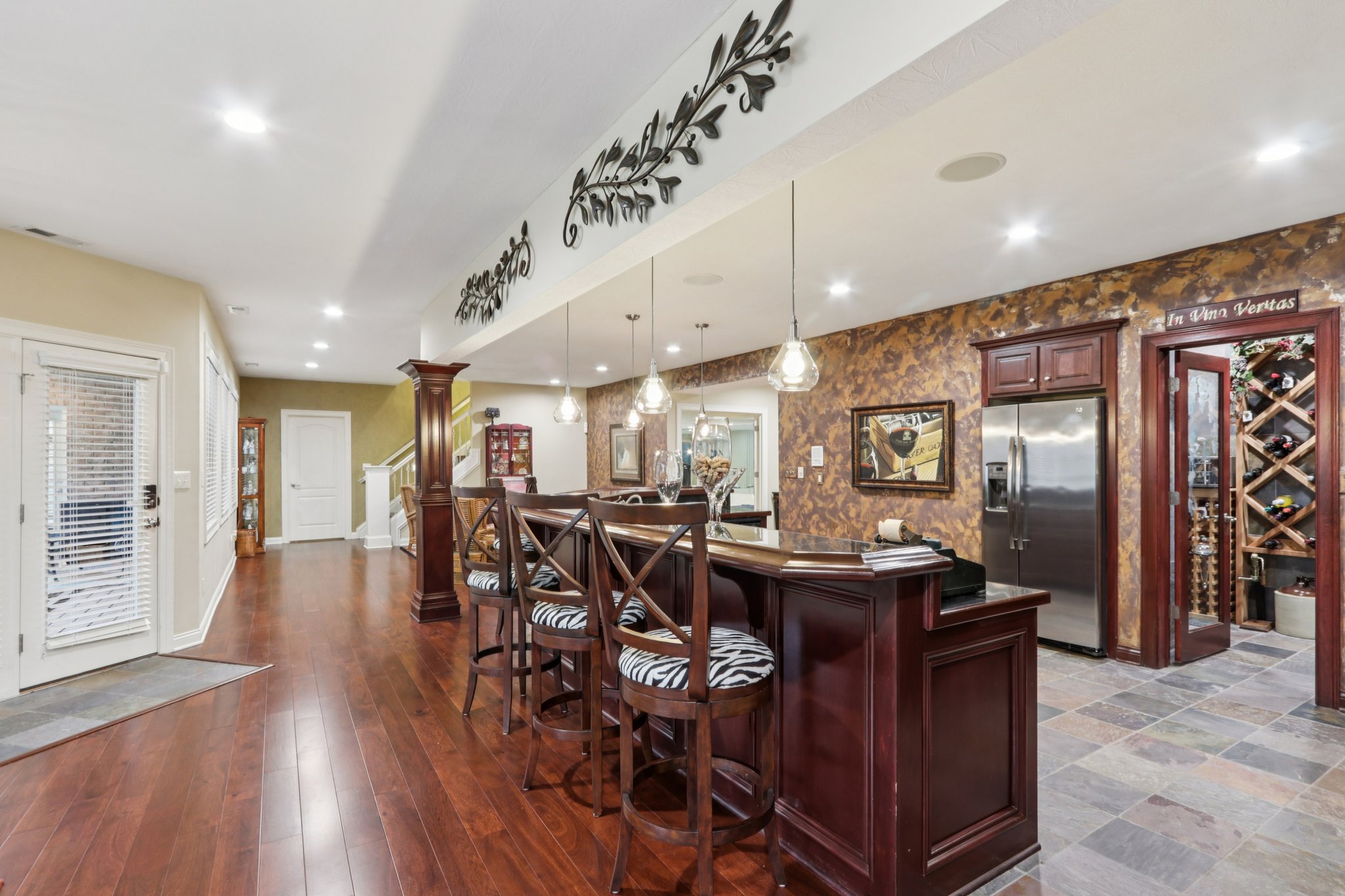 Large bar area with seating, refrigerator, pendant lighting, opens to the large wine cellar