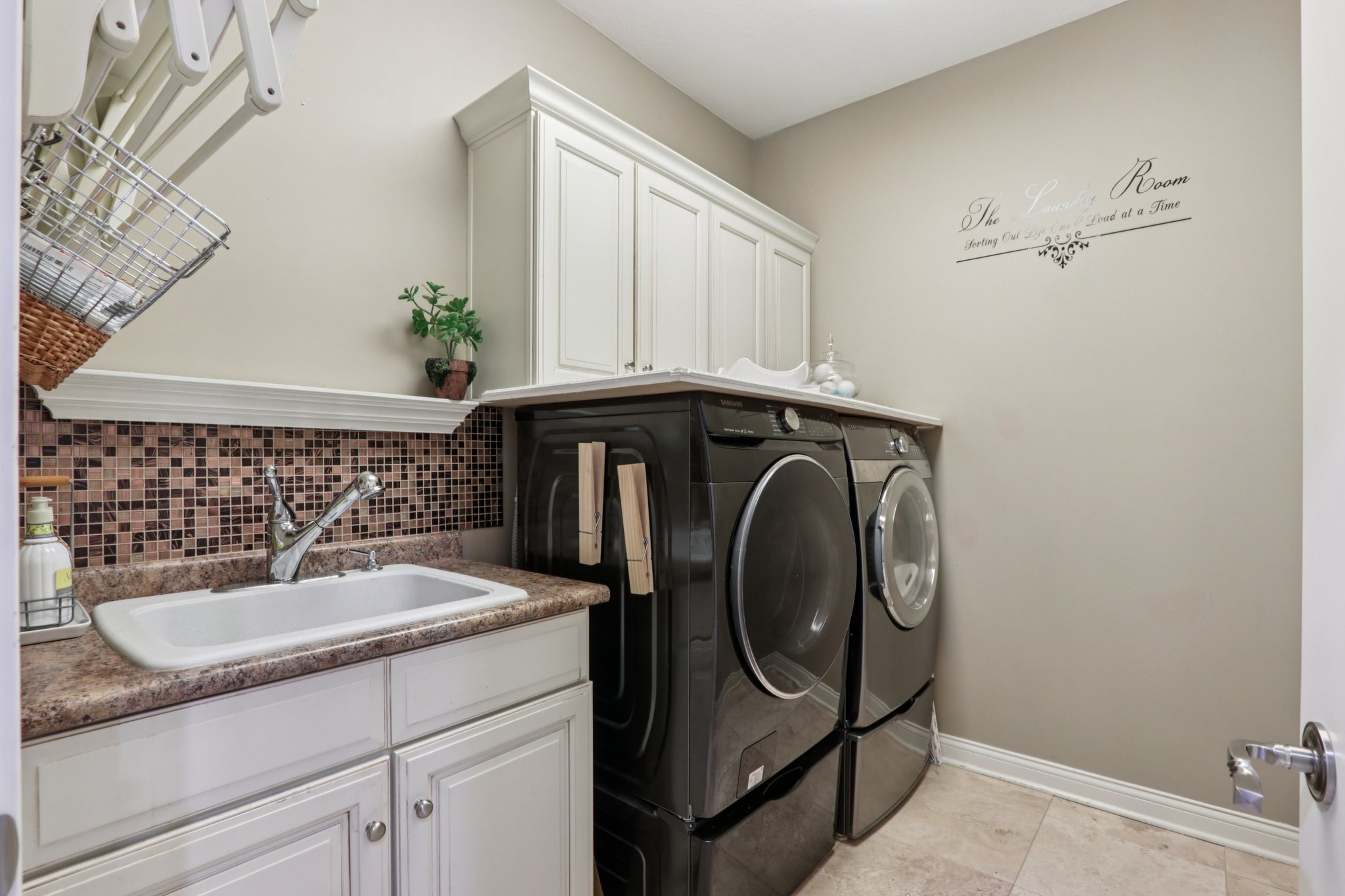 Main level laundry room offers cabinets for storage, cabinet utility sink with washer and dryer included