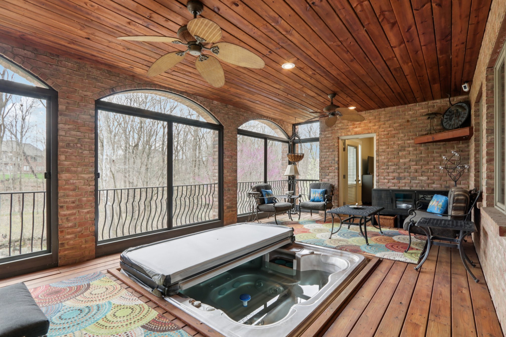 Lower level screened in Lanai offers jacuzzi, and opens to outdoor patio area, seating areas, and stairs to the garden areas and creek with great views of nature