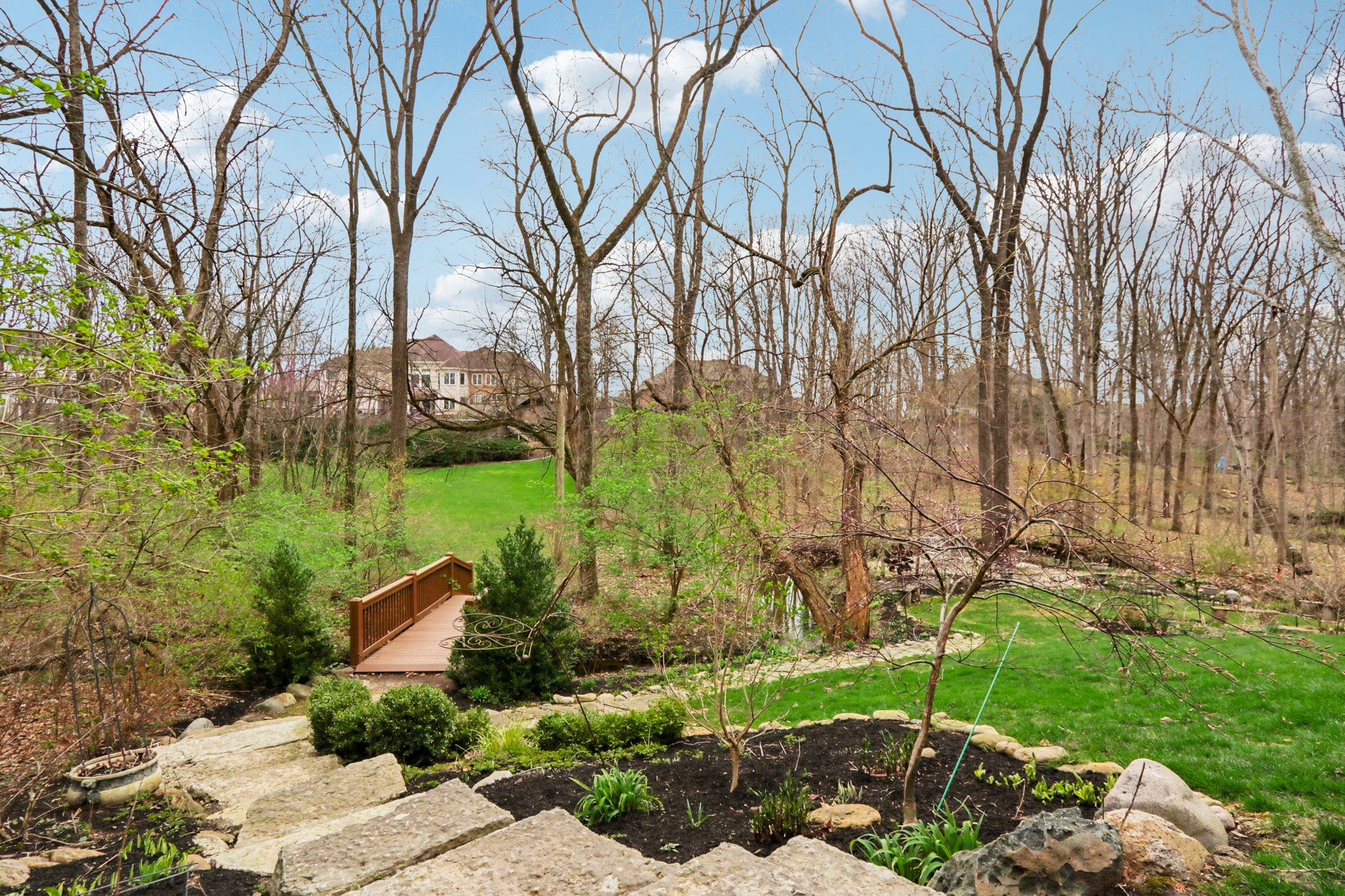 Natural stone stairs lead to the professional landscaped outdoor space with tranquil babbling creek