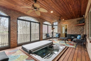 Lower level screened in Lanai offers jacuzzi, and opens to outdoor patio area, seating areas, and stairs to the garden areas and creek with great views of nature