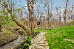 Mature landscaping with pathways along the creek and multiple outdoor seating areas