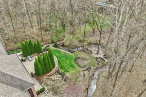 Aerial view showcasing the fabulous backyard offering Belgard paver patio, walkways to multiple seating areas and garden all while enjoying the tranquil creek