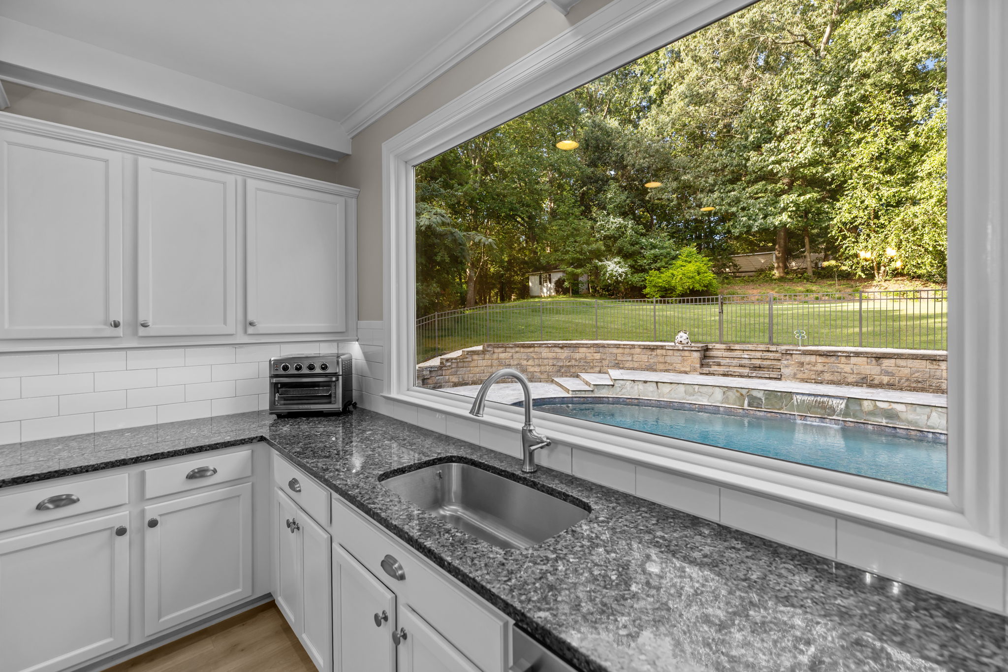 Picture window overlooking serene yard and pool