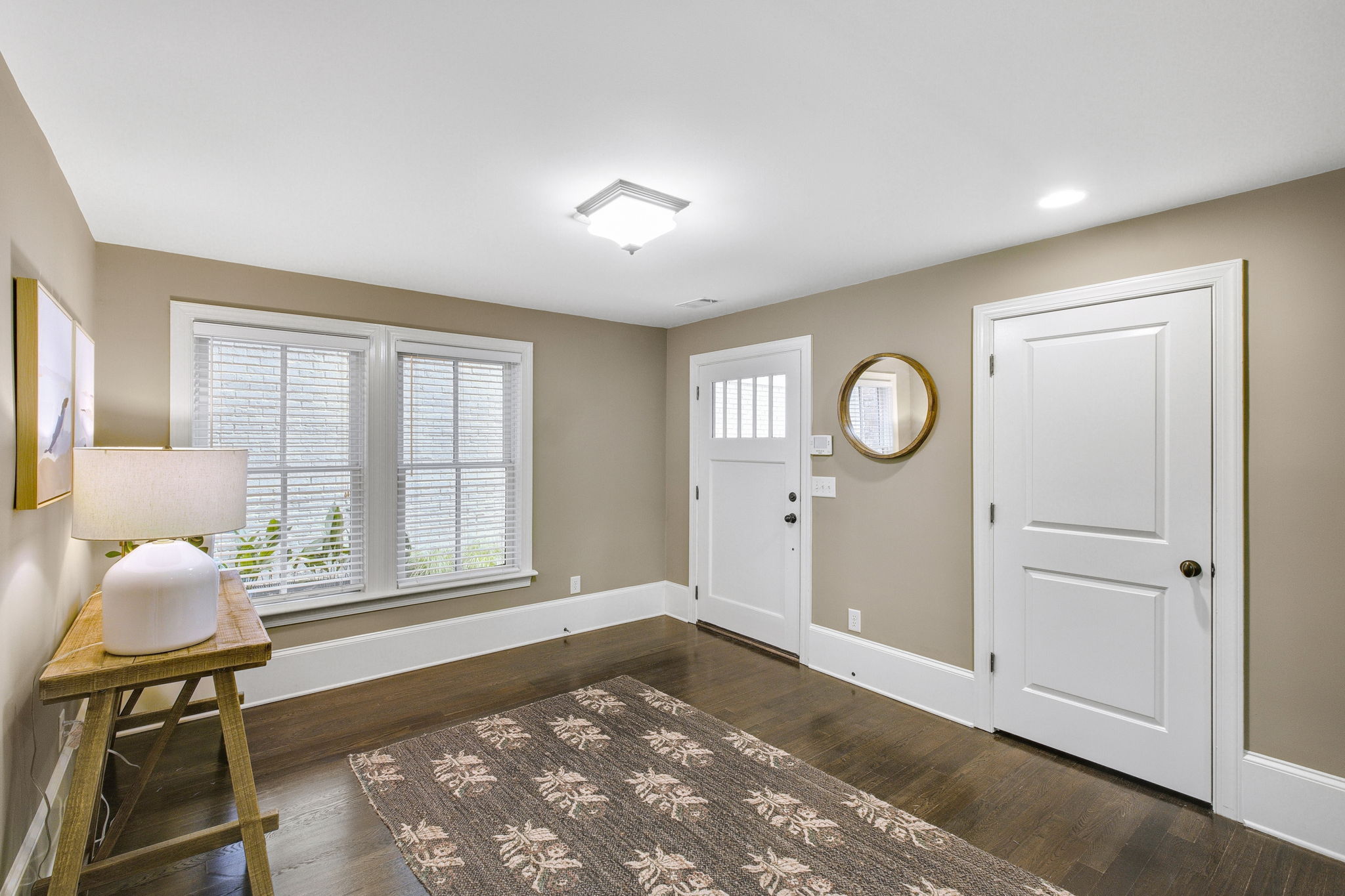 THis foyer has a wall of windows and a coat room.