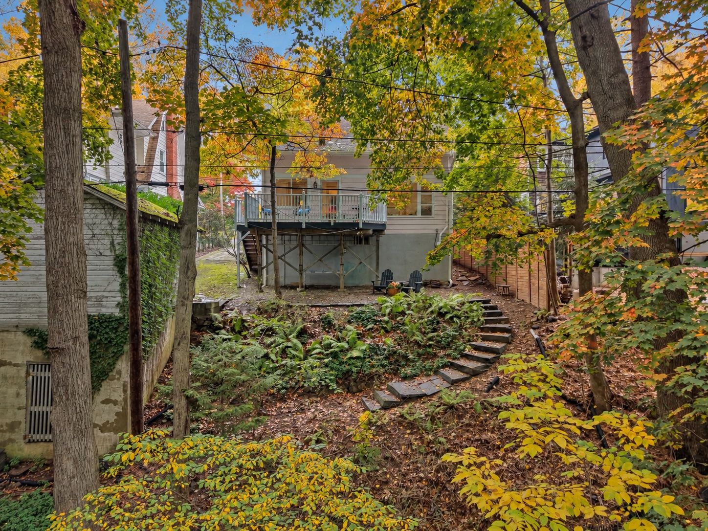 A LITTLE VISION. A LOT OF CHARM. Backview: This vintage two-story garage on the left is ready for a tune-up and a little imagination. Below, a rustic, earth-floored garden cellar opens toward the woods, with potential for potting supplies, garden tools and your next woodland project.