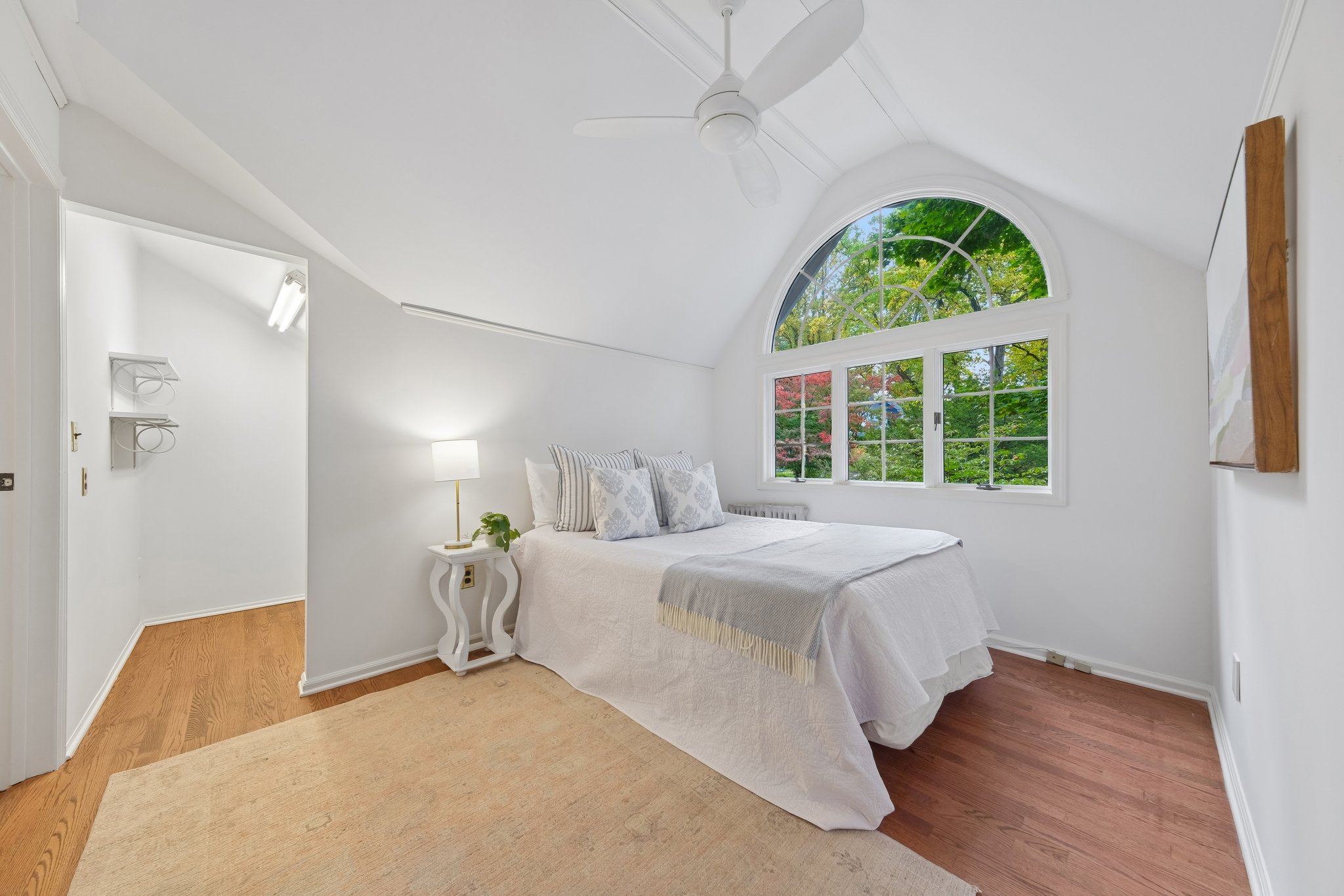 WAKE UP TO SOMETHING LOVELY. An arched window frames the trees, giving this bedroom a wonderfully treehouse-like feeling. Both upstairs bedrooms have cedar closets.