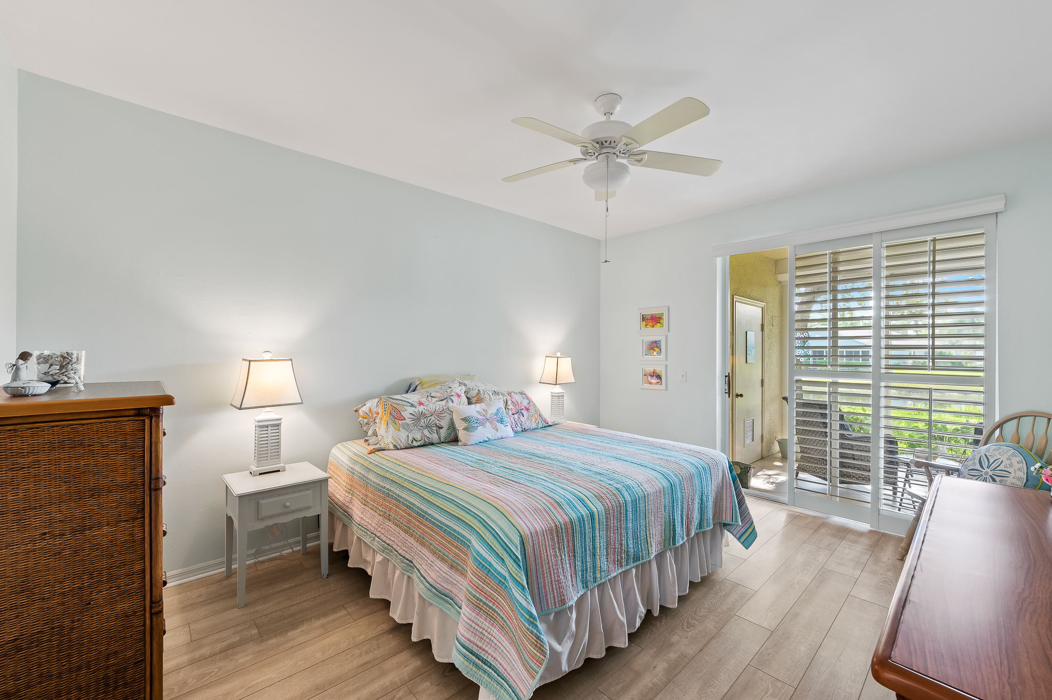 Primary Bedroom with huge walk-in closet and access to lanai. Beautiful water view beyond the sliding plantation shutter panels.
