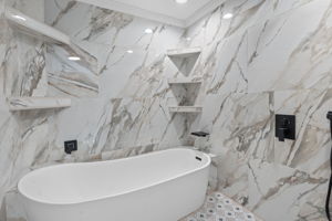 Primary bath's deep soaking tub and dual showers