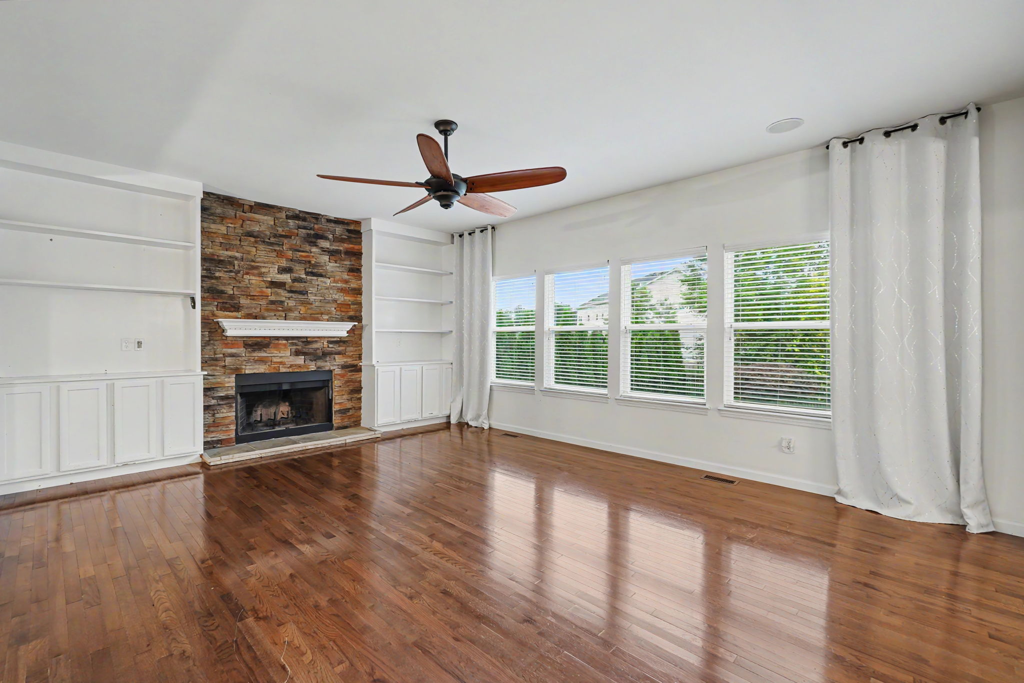 Spacious great room features lots of natural light, built-ins, and stacked stone wood burning fireplace.