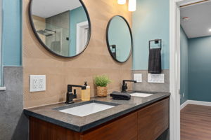 Double floating vanity with black granite counters & designer tile accent wall