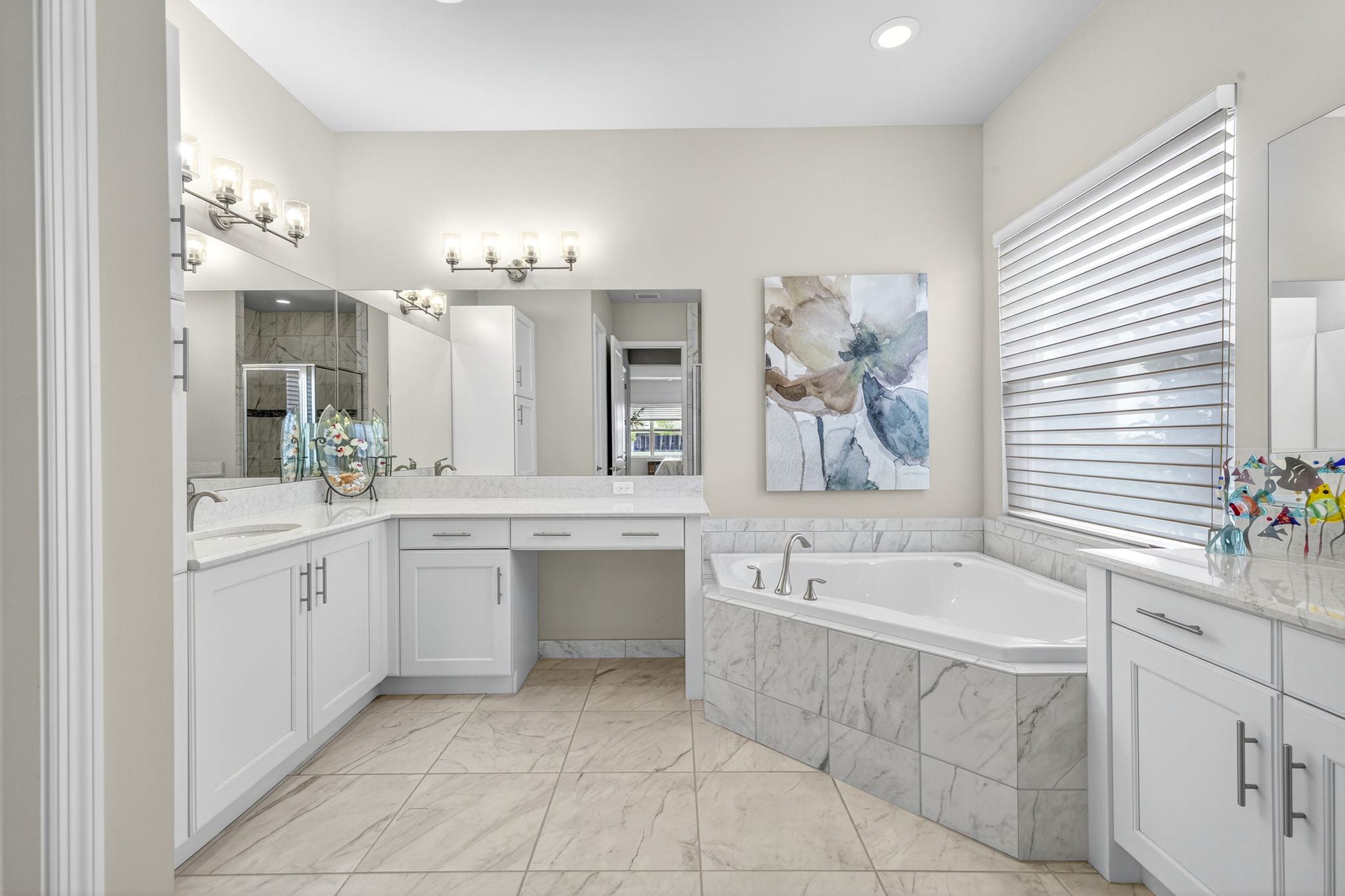 Corner garden tub, vanity area, double sinks, toilet room, and separate glass door shower and linen closet complete this primary bath..