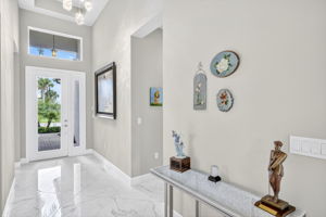 Elegant chandelier in spacious foyer with gleaming porcelain tiles that reflect light!
