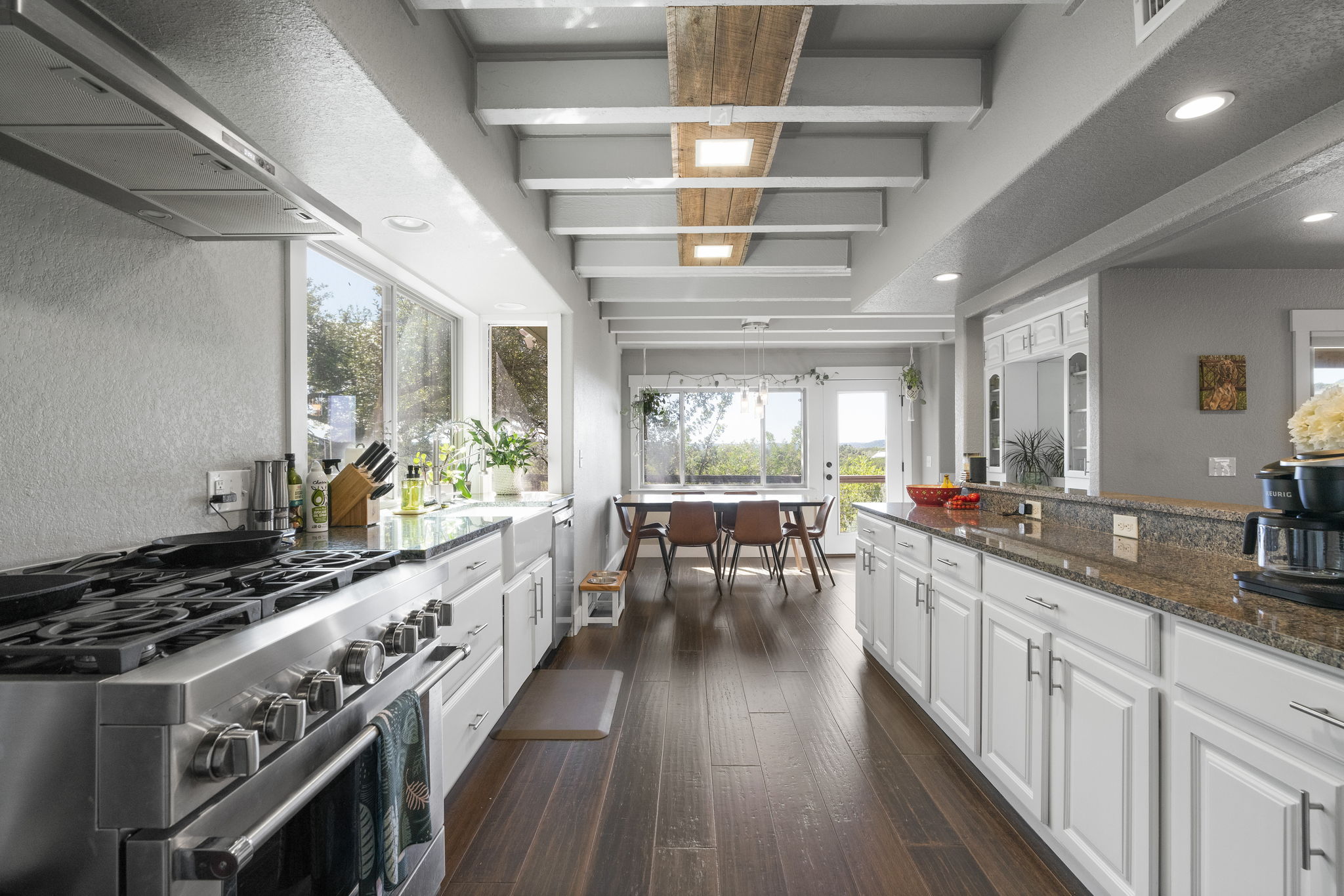 The kitchen boasts a high-end gas stove and granite countertops, seamlessly connecting to the dining and living rooms for a spacious, open feel.