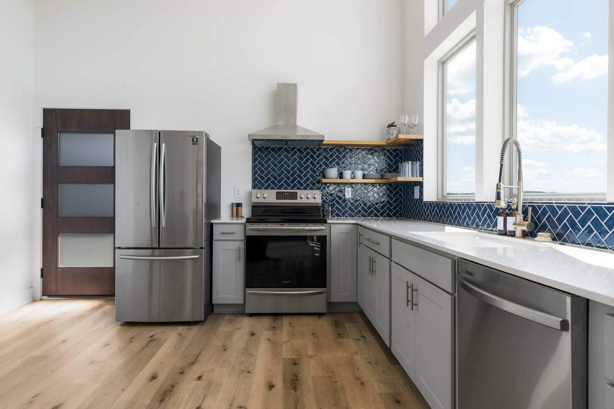 The kitchen is filled with natural light, featuring ample cabinetry, plenty of windows, and beautiful white oak wood floors.