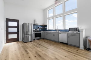 The kitchen is filled with natural light, featuring ample cabinetry, plenty of windows, and beautiful white oak wood floors.