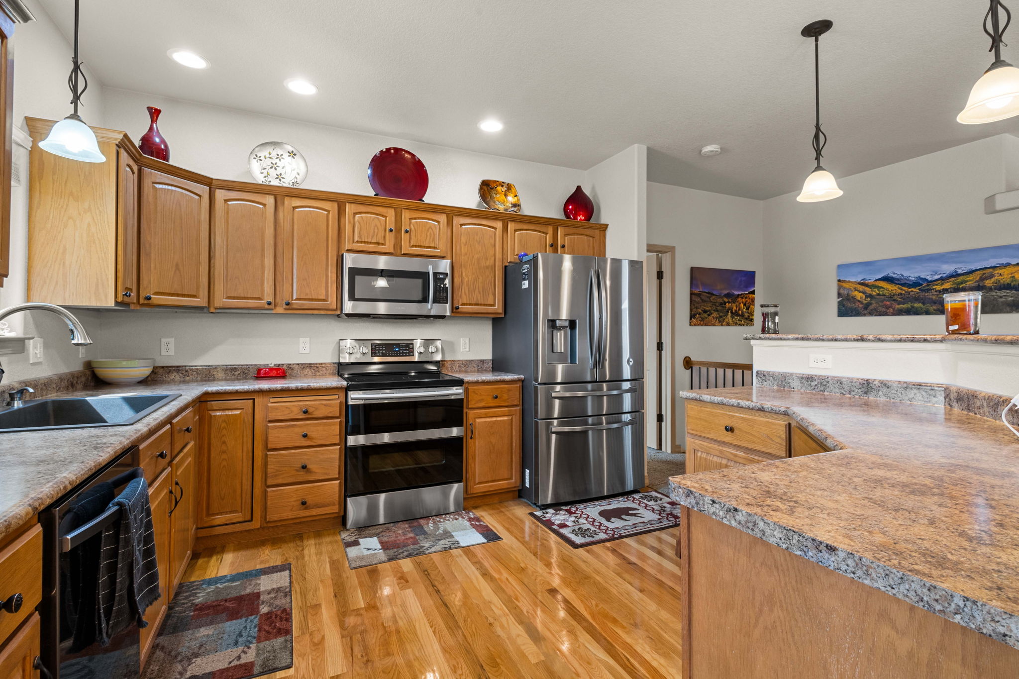 The kitchen has ample storage, high-quality cabinets with elegant crown molding, a convenient high-top island, a sizable pantry, and modern stainless-steel appliances, including an oven that can be utilized as a single unit or split into two, simplifying holiday meal preparations.
