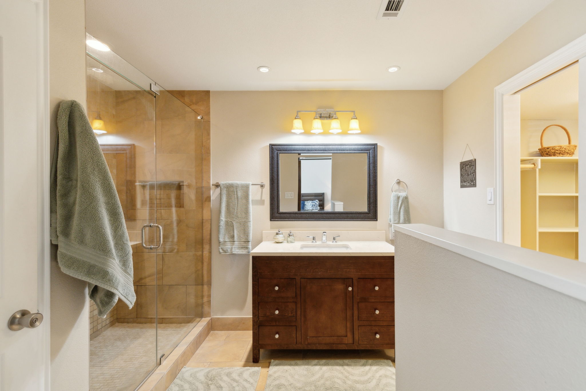 The striking vanity, granite counter, lovely mirror and lighting provide the feel of both elegance and warmth.  To the right is the spacious walk-in closet!
