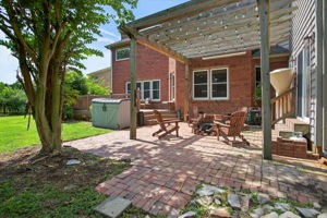 Charming paved patio tucked under a pergola—ideal for cozy evenings, outdoor dining, or shaded lounging.