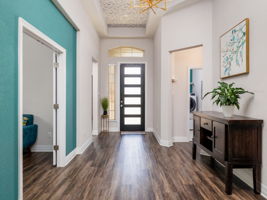 Grand high ceiling entrance featuring: decorative wall paper, bronze lighting, 8 ft modern front door & hallway casings.
