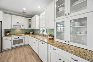 The kitchen continues with generous counter space, glass-front cabinetry, and clean white finishes ...