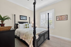 2nd bedroom features a walk-in closet, plantation shutter and plank tile flooring.