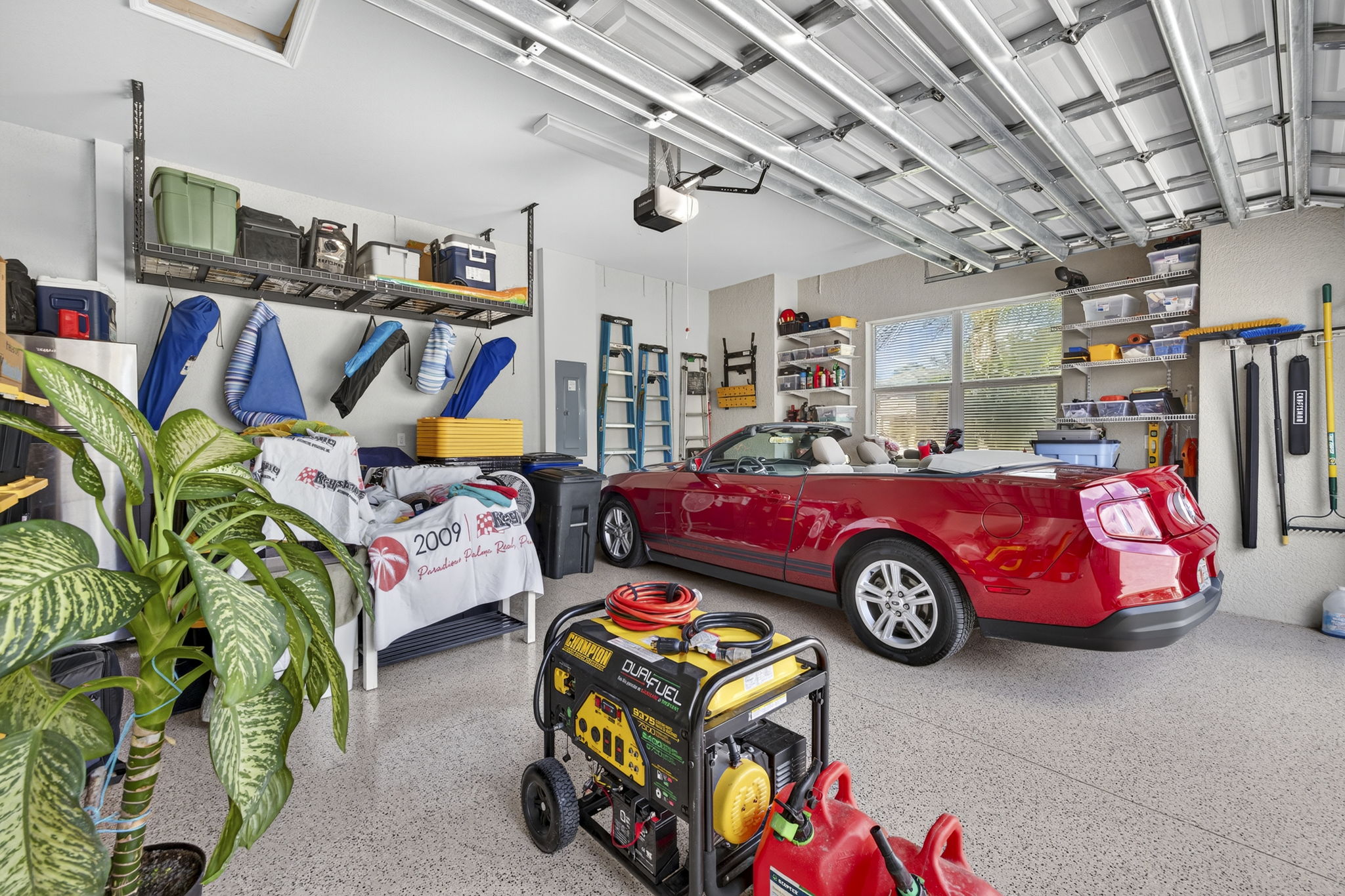 Garage features overhead storage, shelves with hanging brackets, a portable generator, and is oversized.
